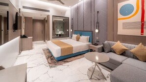 A modern hotel room with a large bed, a sofa, a small table, and a ceiling fan. - Enrise By Sayaji Bhopal (Bhopal)