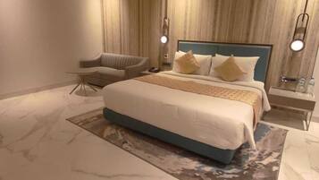 Ein modernes Schlafzimmer mit einem großen Bett, einem Sessel und einem Nachttisch.