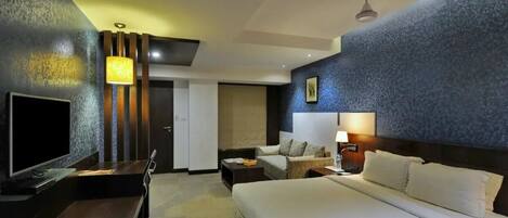 Una habitación de hotel con una cama grande, televisión, escritorio y una silla.