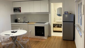 A modern kitchen with built-in appliances, a dining area with a round table and chairs, and a small bathroom with a sink and mirror. - Villa Riviera 287 - Appartamento Pineta (Pescara)