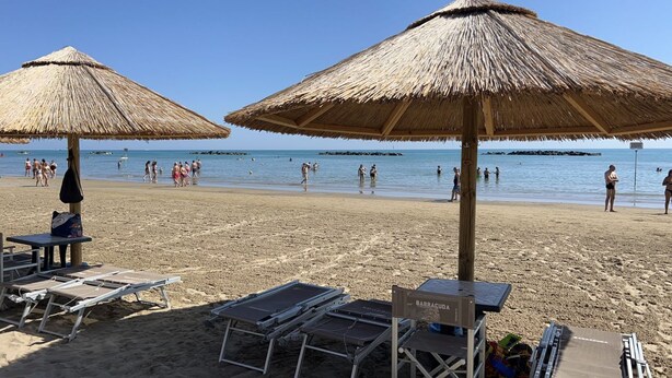 A beach with thatched umbrellas, sun loungers, and a clear view of the sea. - Villa Riviera 287 - Appartamento Pineta (Pescara)