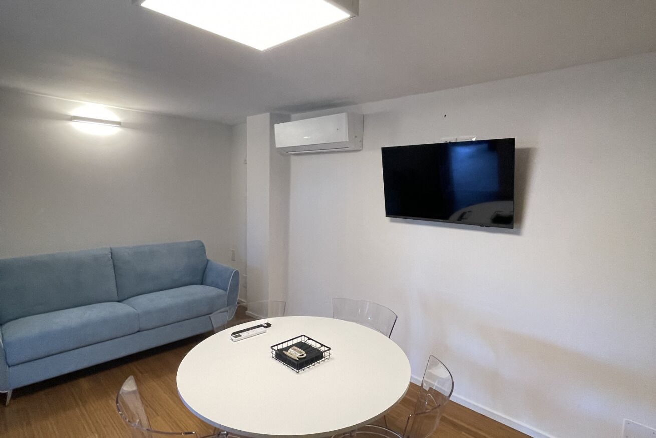 Une chambre moderne équipée d’un canapé, d’une table ronde, d’un téléviseur et d’un appareil de climatisation.