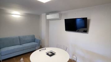 Une chambre moderne équipée d’un canapé, d’une table ronde, d’un téléviseur et d’un appareil de climatisation.