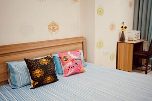 Cozy retreat with a bed, desk, and chair, featuring a vase with fresh flowers.