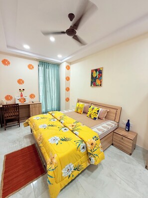 Cozy retreat with a floral-patterned bedspread, ceiling fan, and vibrant artwork.