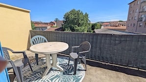 A balcony with a round table and two chairs, a concrete wall, and a view of buildings and trees. - Gîte le Foch, rated 3 ***, large gîte in the center of Albi, ideal for groups/families, (Albi)