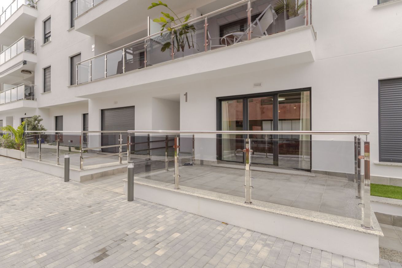 A modern multi-story building with balconies, large windows, and a clean, tiled ground floor.