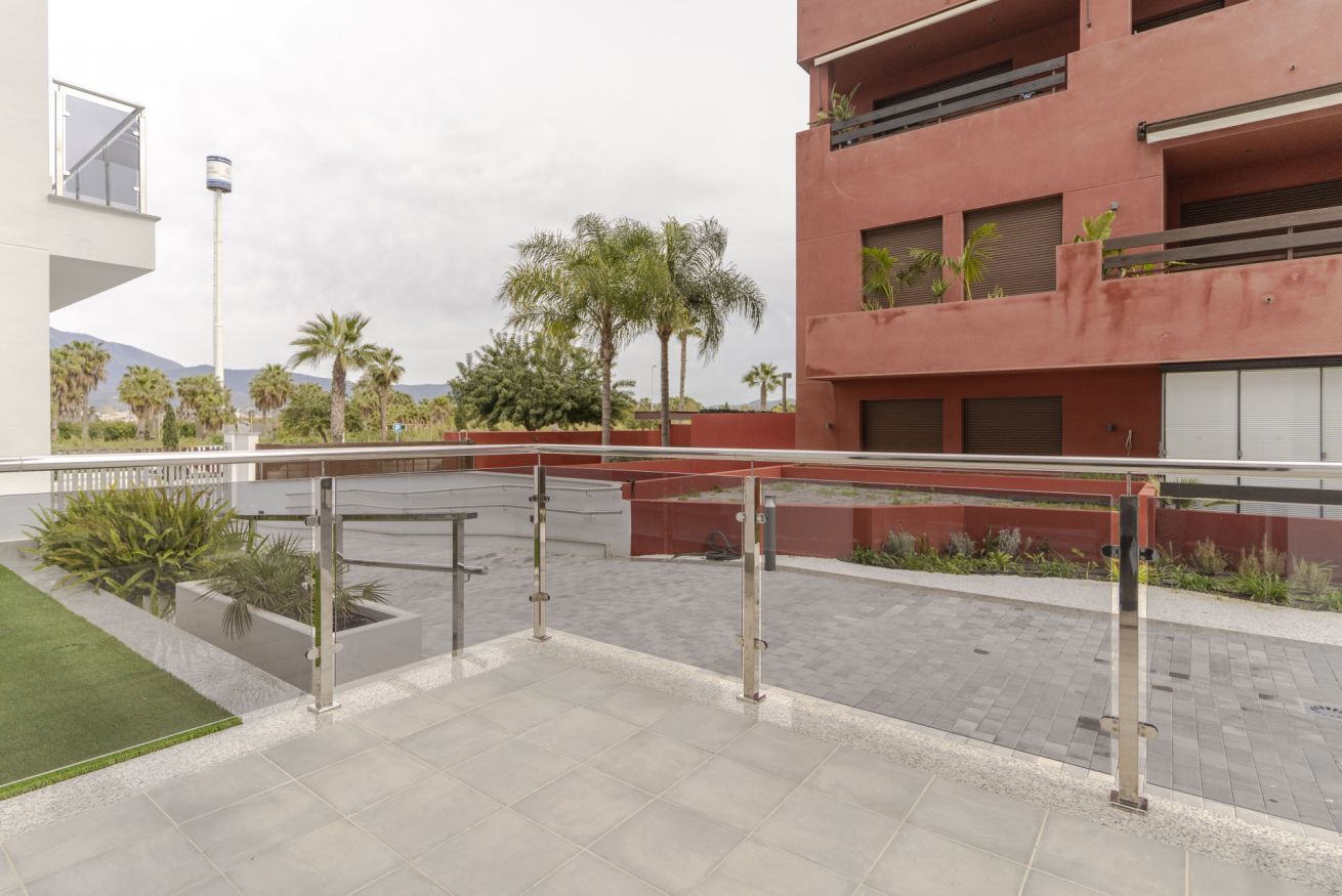 A modern outdoor area with a paved walkway, metal railings, and a grassy patch.