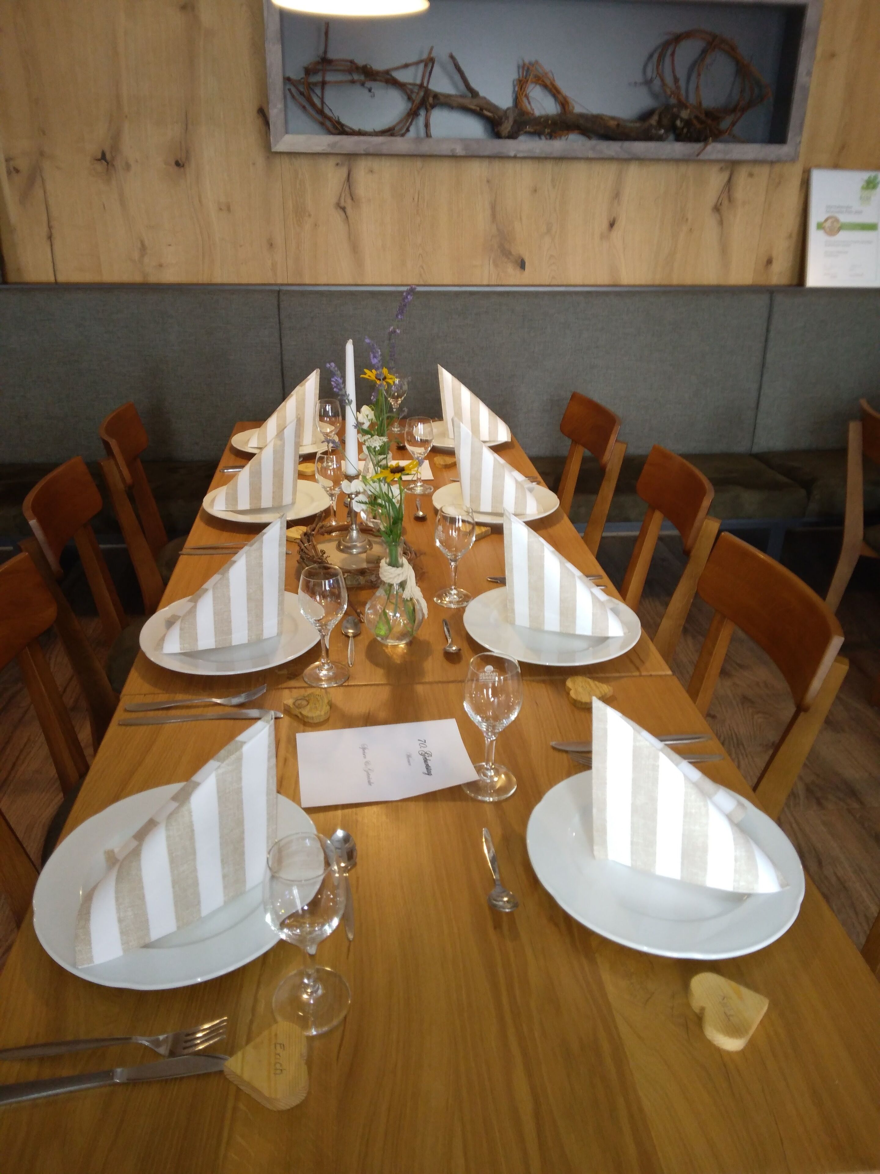 Une table à manger dressée pour six personnes, avec des serviettes à rayures, des assiettes blanches et des verres à vin.