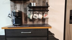 Une petite cuisine équipée d’une machine à café, de tasses et d’une pancarte indiquant : « Lieu de rencontre ».