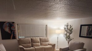 Un salon avec un canapé beige, un fauteuil, une petite table et un lampadaire.