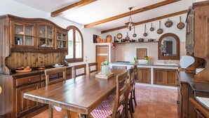 A rustic kitchen with wooden cabinets, a dining table, and a tiled backsplash.