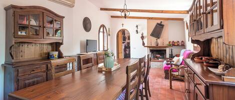 Una cocina tradicional con armarios de madera, una mesa de comedor grande y una chimenea.