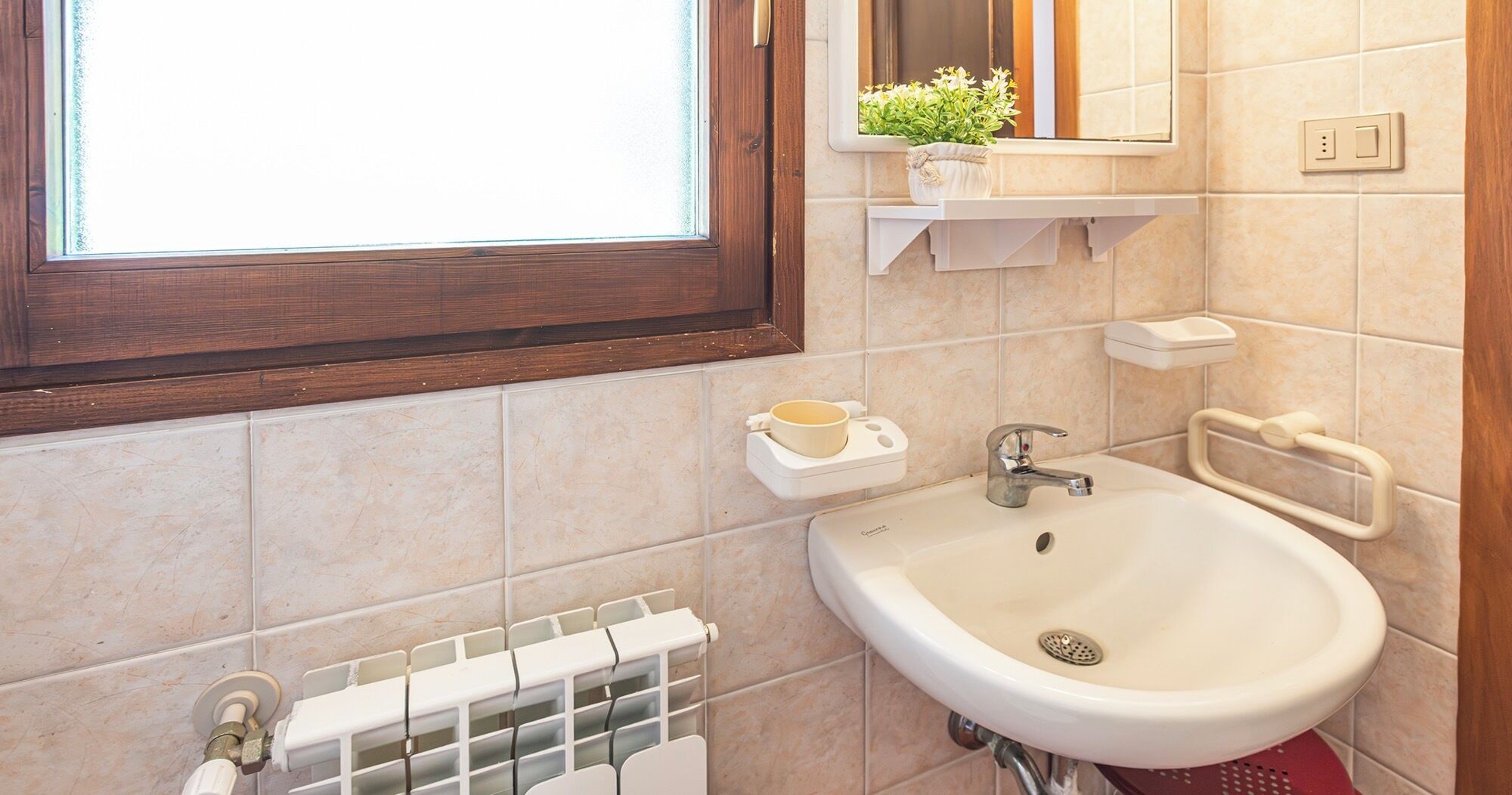 Ein Badezimmer mit Waschbecken, Spiegel, Fenster und Handtuchhalter.