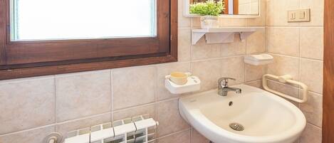 Ein Badezimmer mit Waschbecken, Spiegel, Fenster und Handtuchhalter.