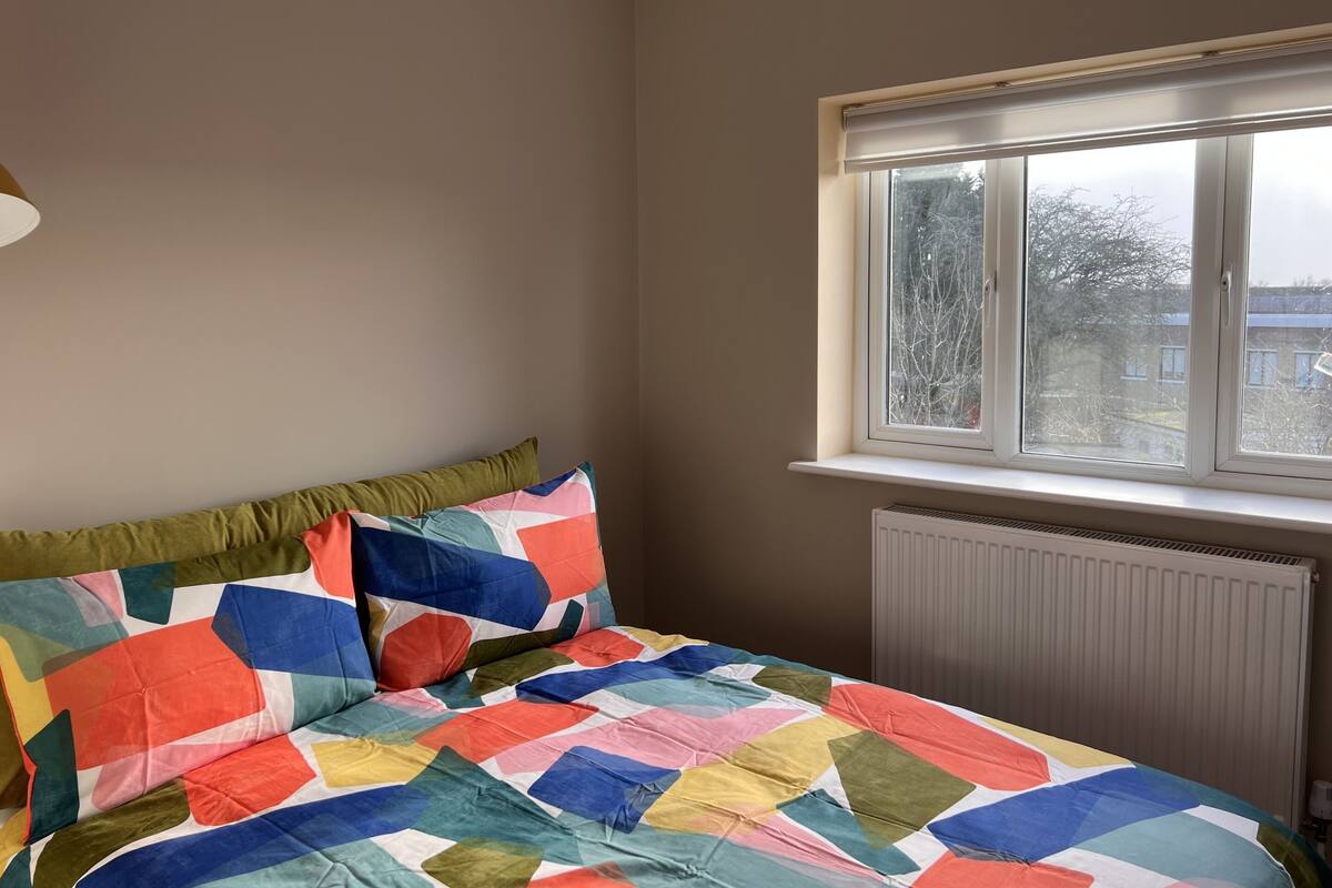 A bedroom with a bed, a window, and a radiator.