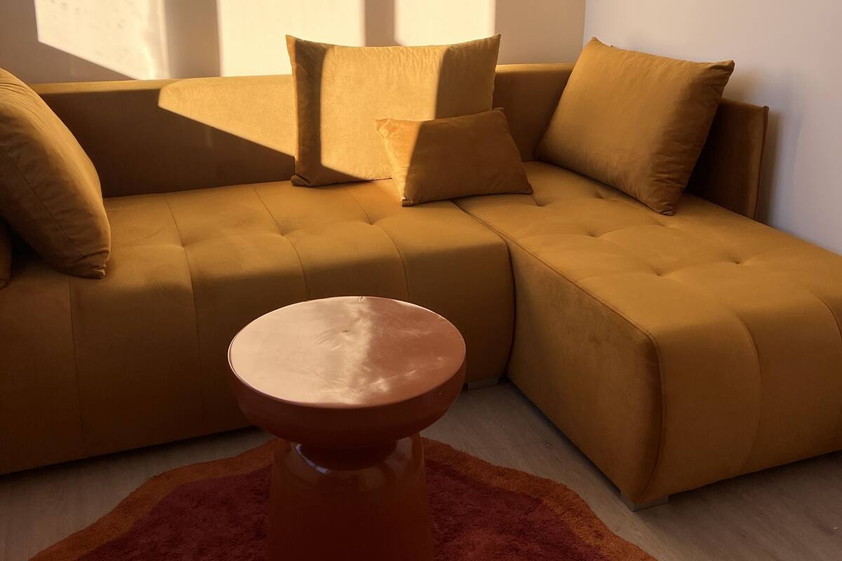 A modern living room with a sectional sofa, a round coffee table, and a red rug.