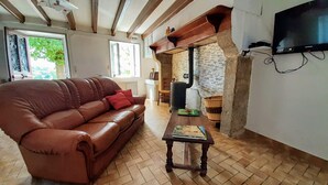 Una sala de estar acogedora con un sofá de cuero marrón, una mesa de centro de madera y un televisor montado en la pared.