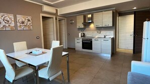 A modern kitchen with white cabinets, a built-in oven, and a dining area with a white table and chairs. - 11. Appartmento (Signa)