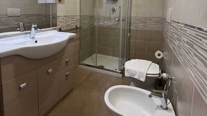 A modern bathroom with a glass-enclosed shower, a sink, and a bidet. - 11. Appartmento (Signa)