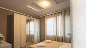 A modern hotel room with a large bed, a desk, and a mirror. - 11. Appartmento (Signa)