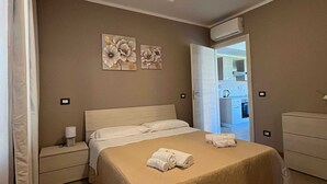 A bedroom with a bed, nightstands, a dresser, and a ceiling light. - 11. Appartmento (Signa)