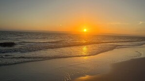 Escena de platja amb el sol ponent-se sobre l'oceà.