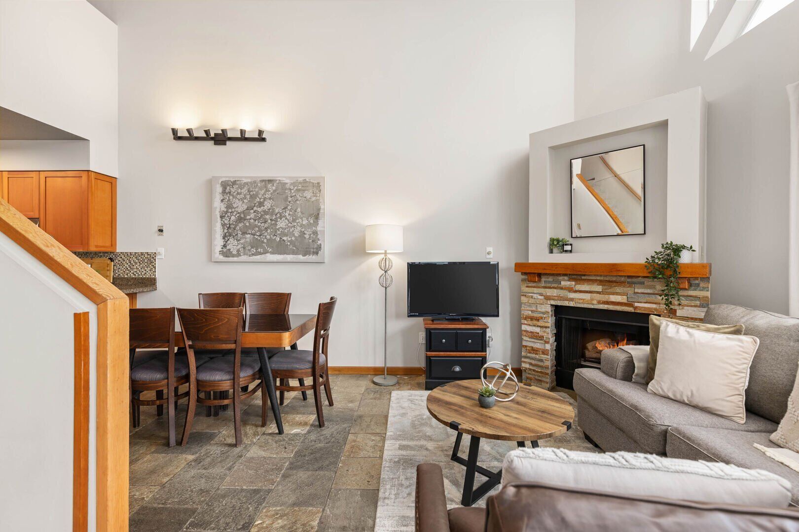 A living room with a fireplace, a television, and a dining area with chairs and a table.