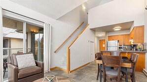 Una sala de estar moderna con un sofá de cuero marrón, una mesa de centro de madera y un comedor con sillas y mesa de madera.