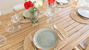 A wooden dining table set with plates, cutlery, and wine glasses, accompanied by a vase of flowers. - Newly built villa in prime location in Jan Thiel, pool and private parking (Willemstad)