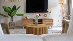 A modern living room with a flat-screen TV, wooden furniture, a round coffee table, and a potted plant. - Newly built villa in prime location in Jan Thiel, pool and private parking (Willemstad)