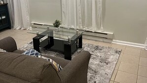 A living room with a glass coffee table, two sofas, a rug, and a small plant.