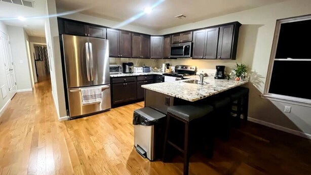 A modern kitchen with dark wood cabinets, stainless steel appliances, and a granite countertop.