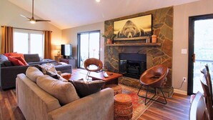 A living room with a sofa, chairs, a fireplace, a television, and a stone wall.
