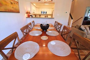 Una mesa de comedor con individuales y un bol en el centro, rodeada de sillas de madera.