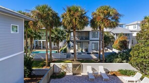 A residential area with a swimming pool, palm trees, and a gated entrance.