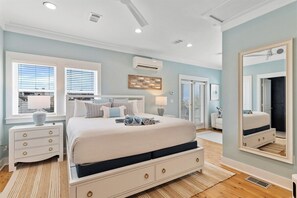 A bedroom with a bed, bedside tables, a mirror, and a window.
