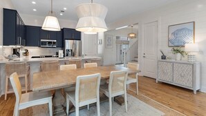 Una cucina moderna con pensili scuri, un'isola in legno e un'area pranzo con sedie in vimini.