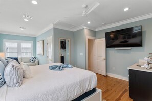 A bedroom with a bed, a ceiling fan, a TV, and a bathroom door. - 30A | 2 Mins to Beach | Private Pool & Beach! (Inlet Beach)