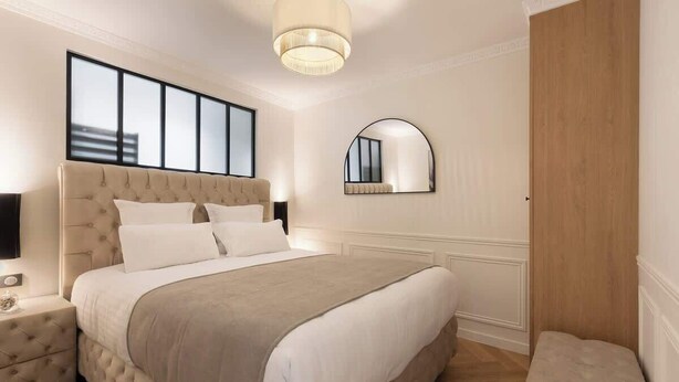 Un dormitorio con una cama grande, una mesita de noche, un espejo y una puerta de madera.