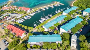 Luftaufnahme einer Marina mit mehreren vertäuten Booten, umgeben von Gebäuden mit roten Dächern und einem großen Gebäude mit blauem Dach.