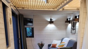 A cozy living area with a sofa, a small table, and a TV. - The TINY HOUSE at Le Haras. (Avrillé)