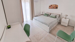 A bedroom with a bed, a bedside table, a chair, a desk, and a painting on the wall. - Holy Dove - Giò Giò by Wonderful Italy (Cefalù)