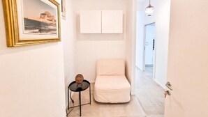 A hallway with a white chair, a small table with a decorative item, and a framed picture on the wall. - Holy Dove - Giò Giò by Wonderful Italy (Cefalù)