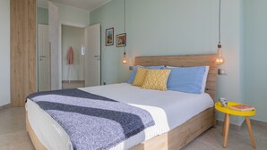 A bedroom with a bed, a wooden headboard, a bedside table with a book, and a hanging light fixture.