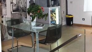 A modern room with a glass table, two chairs, a vending machine, and a trash bin. - 12. Apartment (Signa)