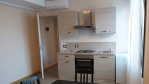 A compact kitchen with a dining table, chairs, a stove, and a dishwasher. - 12. Apartment (Signa)