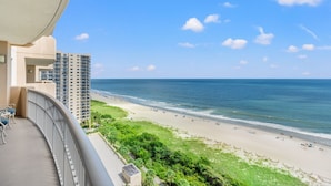 A balcony with a view of a beach and ocean.