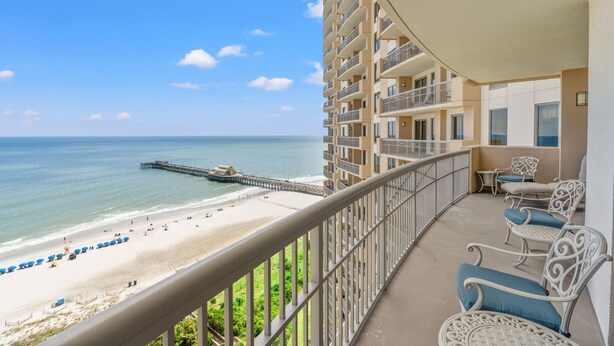 A balcony with a view of a beach and pier.
