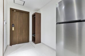 A hallway with a wooden door, a built-in shelving unit, and a stainless steel refrigerator. - hotel onggi (Gyeongju)